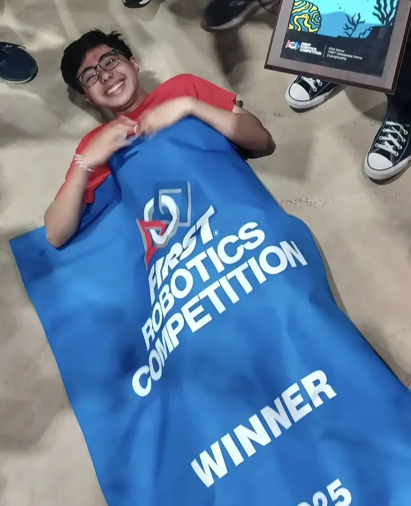 Rayyan Rehman with the FIRST Robotics district championship banner